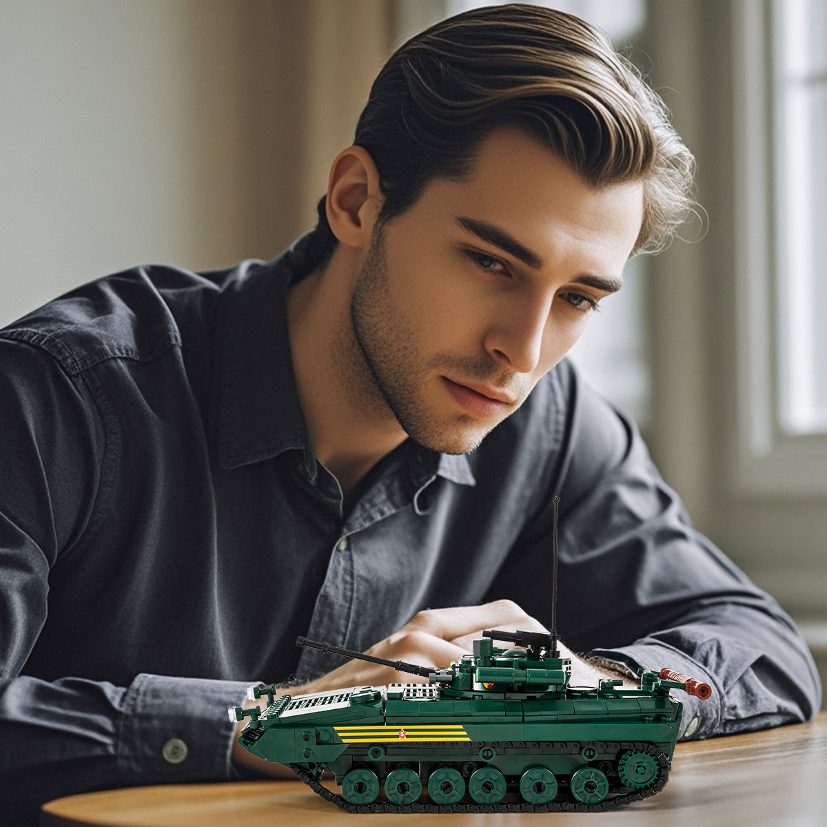 Adult builder displaying the assembled BMP infantry tank block set on a wooden table at home